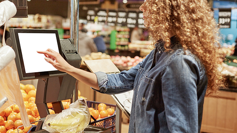 Person weighing fruit at scale in grocery store
