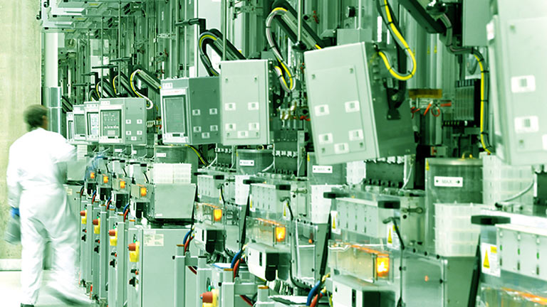 Engineer alongside industrial machines arranged in a line