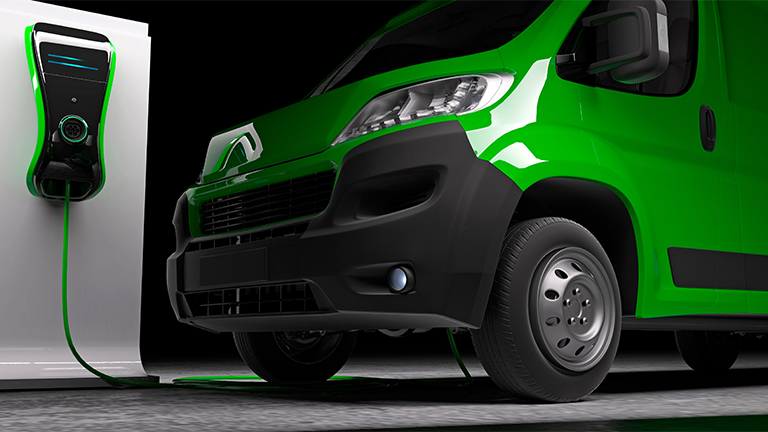 a green electric van being charged