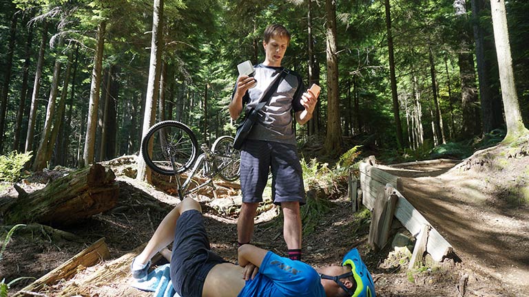 Injured man being cared for by another man in forest