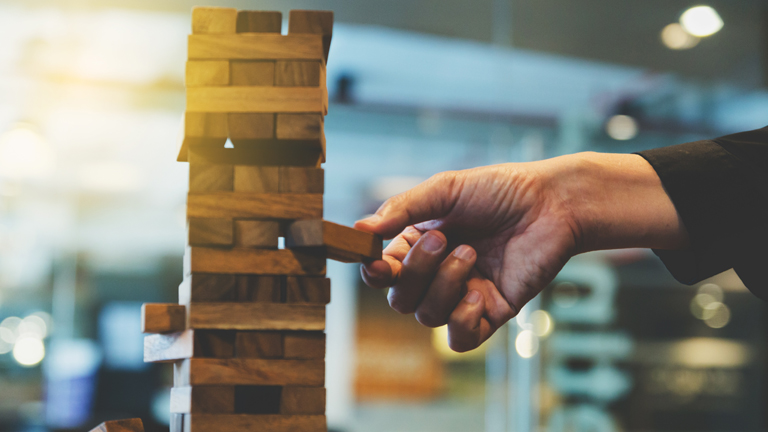 A hand removing a tile from the game of Jenga