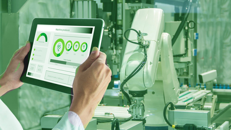 Hands holding a tablet showing data, with an industrial robot in the background