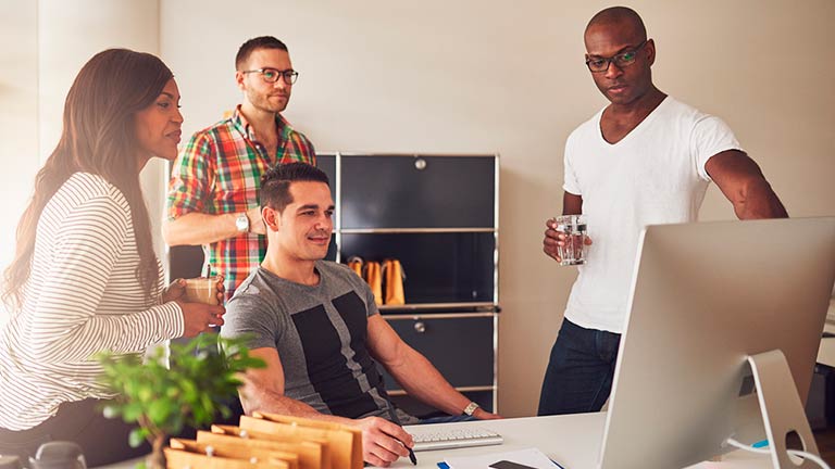 young professionals in office setting around computer screen
