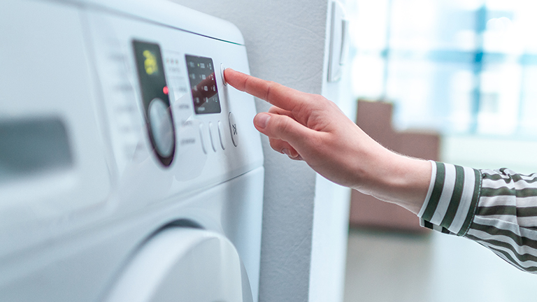 Washing machine, person touching dials to program it. Washing machine, person touching dials to program it.