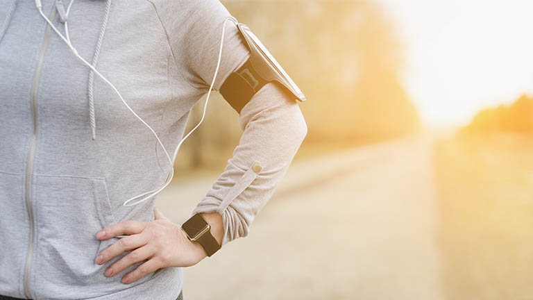 Person with apple watch and ear phone linked to a mobile phone armband